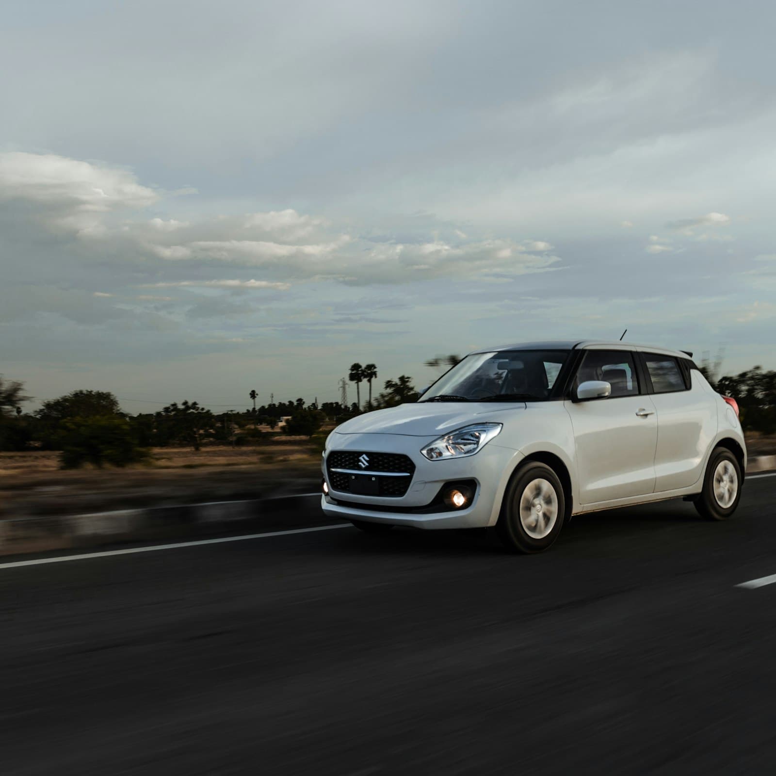 White hatchback driving on an Indian highway